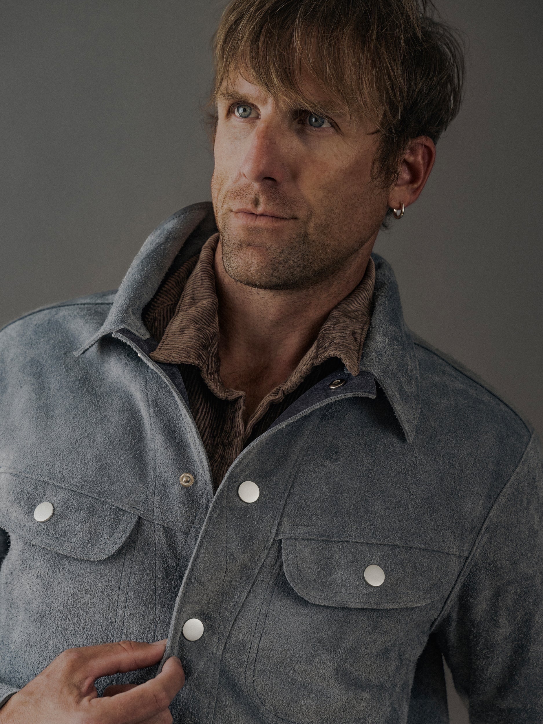 David Dangelo Caldwell light blue suede trucker jacket with exposed seams and silver snap buttons, worn over a brown corduroy shirt.
