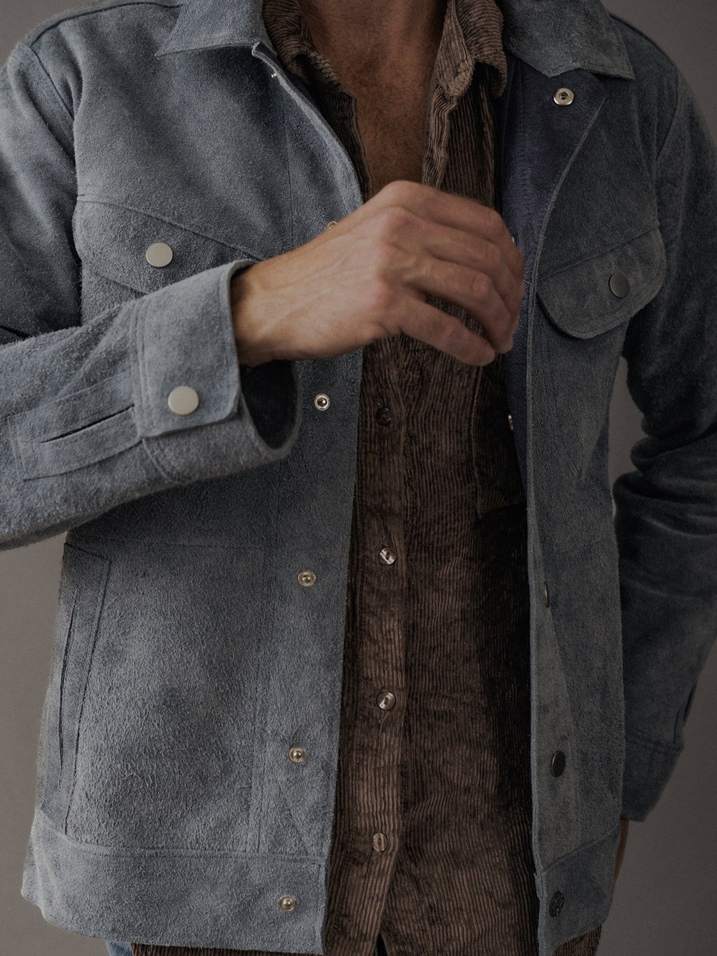 David Dangelo Caldwell light blue suede trucker jacket with exposed seams and silver snap buttons, worn over a brown corduroy shirt.