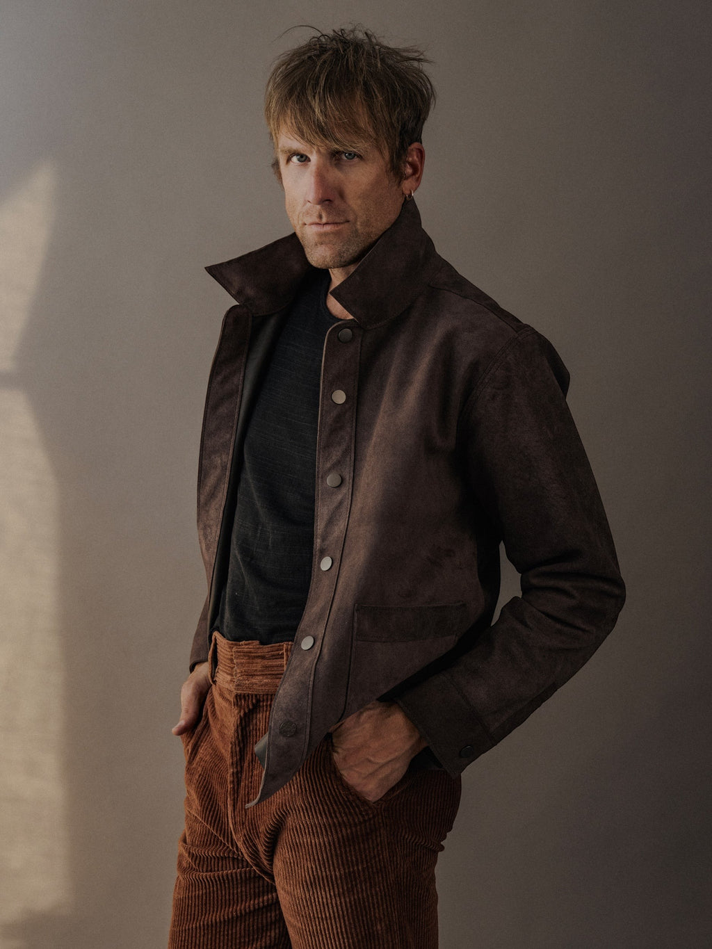 David Dangelo Caldwell brown suede leather jacket with patch pockets and custom hardware, worn by a man with corduroy pants.