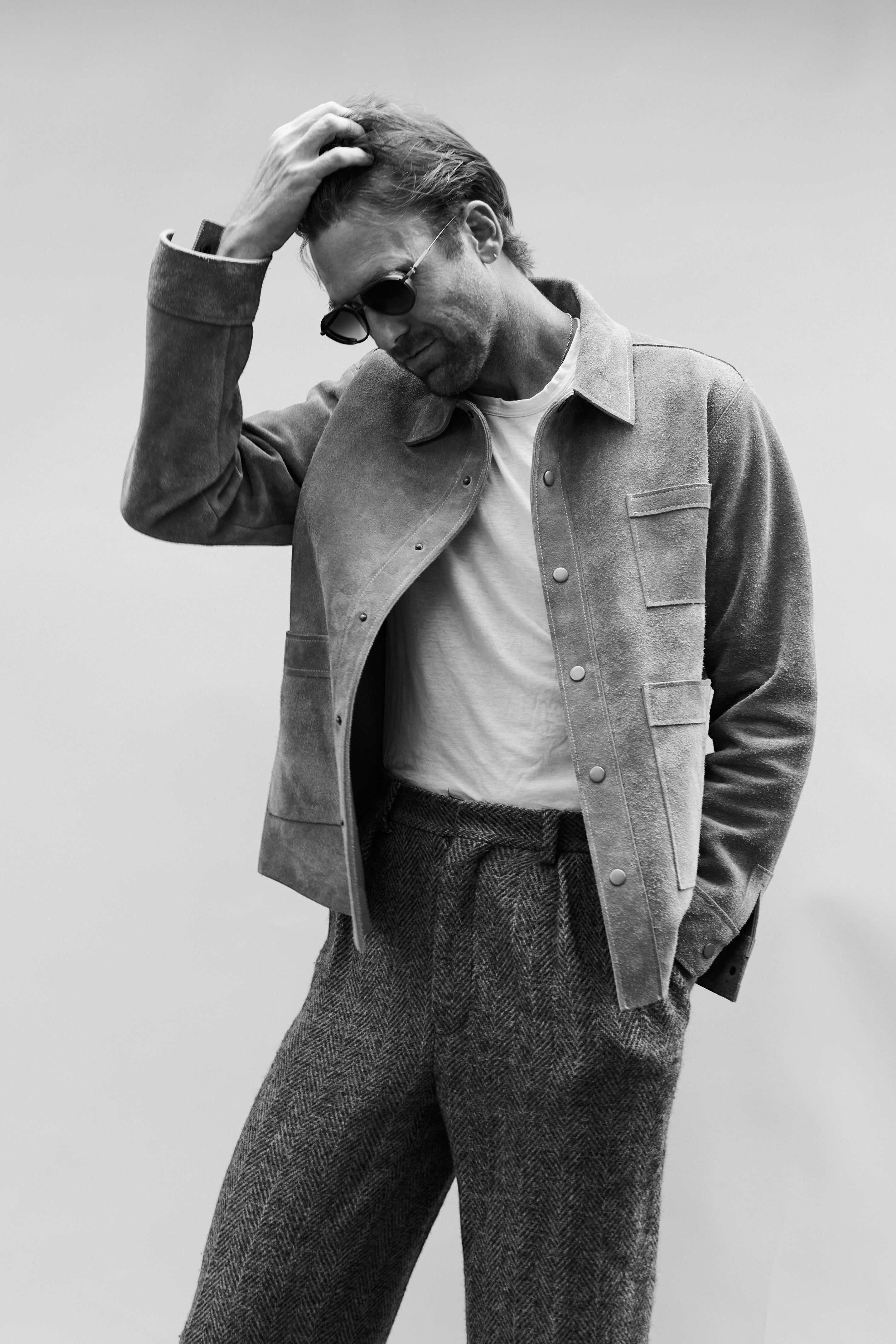 David Dangelo Caldwell grey suede jacket with two patch pockets, worn over a white t-shirt and herringbone trousers.