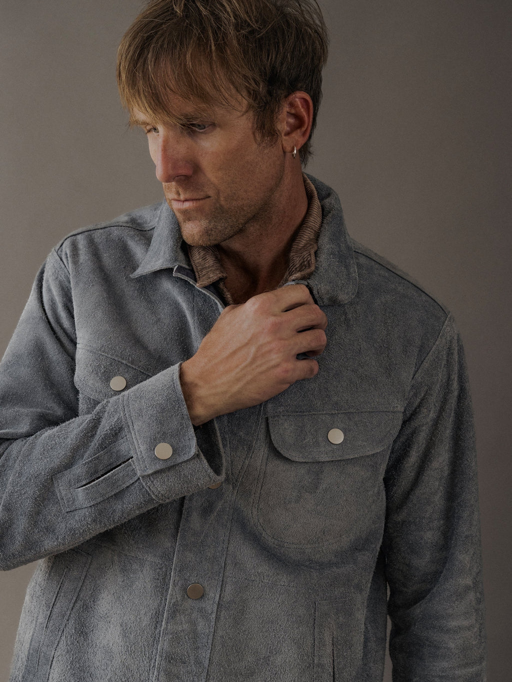 David Dangelo Caldwell grey suede trucker jacket with exposed seams and silver button details, designed for a classic fit and reversible wear.