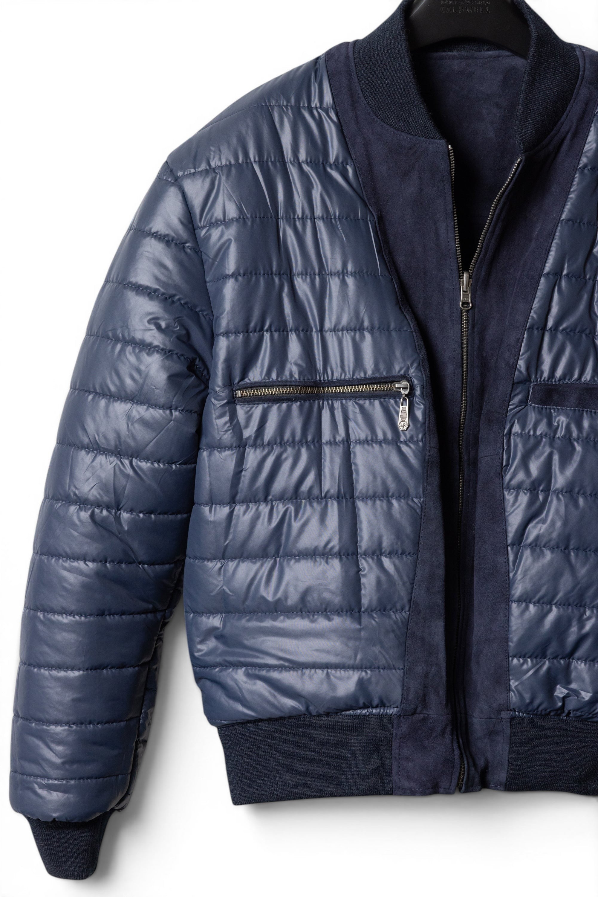 David Dangelo Caldwell navy blue reversible bomber jacket with puffer exterior and suede accents. Features zip pockets and ribbed cuffs.