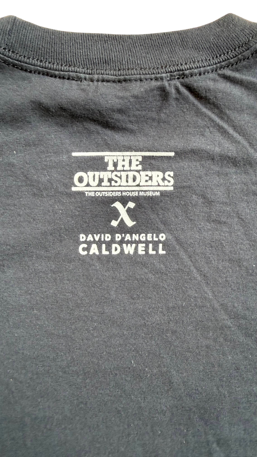 David Dangelo Caldwell black 100% cotton Tulsa Greaser's Club t-shirt with The Outsiders Museum logo.